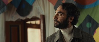 Movie still from “The Kite Runner” (2007), directed by Marc Forster – A man with long hair and a beard wearing a suit; Close Up shot, Low angle