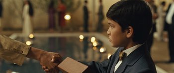 Movie still from “The Kite Runner” (2007), directed by Marc Forster – A young boy in a suit holding a book; Close Up shot, Over the shoulder angle