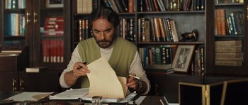 Movie still from “The Kite Runner” (2007), directed by Marc Forster – A man sitting at a table looking at a piece of paper; Medium shot, Low angle