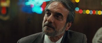 Movie still from “The Kite Runner” (2007), directed by Marc Forster – A person wearing a suit and tie; Close Up shot, Over the shoulder angle