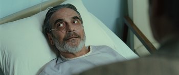 Movie still from “The Kite Runner” (2007), directed by Marc Forster – An older man laying in a hospital bed with his eyes wide open; Close Up shot, High angle