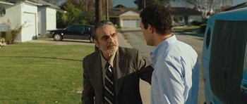 Movie still from “The Kite Runner” (2007), directed by Marc Forster – A man in a suit and tie talking to another man in a dress shirt and tie; Medium shot, Over the shoulder angle