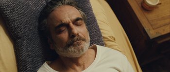 Movie still from “The Kite Runner” (2007), directed by Marc Forster – An older man sleeping on a couch with his eyes closed; Close Up shot, High angle