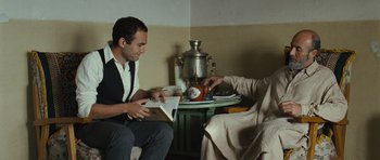 Movie still from “The Kite Runner” (2007), directed by Marc Forster – A man and a woman sitting at a table with a tea pot on it; Medium shot, Over the shoulder angle