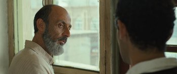 Movie still from “The Kite Runner” (2007), directed by Marc Forster – A man with a beard looking out of a window; Close Up shot, Over the shoulder angle