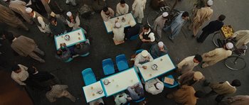 Movie still from “The Kite Runner” (2007), directed by Marc Forster – A group of people sitting at tables eating food; Extreme Wide shot, Overhead angle