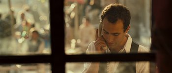 Movie still from “The Kite Runner” (2007), directed by Marc Forster – A man talking on a cell phone while sitting at a table; Close Up shot, High angle
