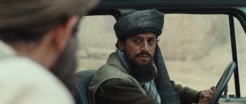 Movie still from “The Kite Runner” (2007), directed by Marc Forster – A man with a beard wearing a hat sitting in the back of a car; Close Up shot, Over the shoulder angle