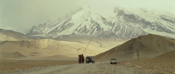 Movie still from “The Kite Runner” (2007), directed by Marc Forster – A group of cars parked on a dirt road near a mountain range; Extreme Wide shot, Low angle