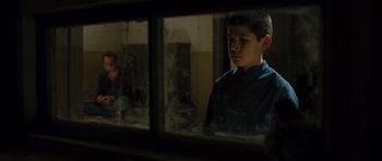 Movie still from “The Kite Runner” (2007), directed by Marc Forster – A young boy looking out of a window at a woman; Medium shot, Over the shoulder angle