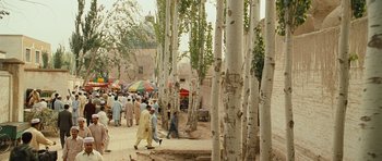 Movie still from “The Kite Runner” (2007), directed by Marc Forster – A group of people walking down a street next to trees; Extreme Wide shot, Low angle