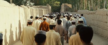 Movie still from “The Kite Runner” (2007), directed by Marc Forster – A large group of men in white hats are walking down the street; Extreme Wide shot, High angle