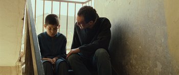 Movie still from “The Kite Runner” (2007), directed by Marc Forster – A man sitting next to a young boy in front of a window; Medium shot, Over the shoulder angle