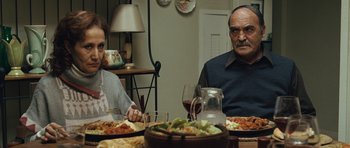 Movie still from “The Kite Runner” (2007), directed by Marc Forster – A man and a woman sitting at a dinner table with plates of food; Medium shot, Over the shoulder angle