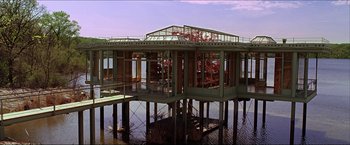 Movie still from “The Lake House” (2006), directed by Alejandro Agresti – A building that is under construction next to a body of water; Extreme Wide shot, Low angle