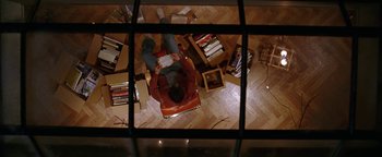 Movie still from “The Lake House” (2006), directed by Alejandro Agresti – A man laying on the floor reading a book; Wide shot, Overhead angle