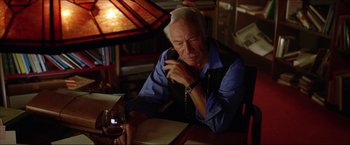 Movie still from “The Lake House” (2006), directed by Alejandro Agresti – An older man talking on a phone while holding a glass of wine; Medium shot, Low angle