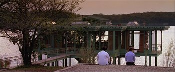 Movie still from “The Lake House” (2006), directed by Alejandro Agresti – A man sitting on the edge of a pier looking out over the water; Extreme Wide shot, Over the shoulder angle