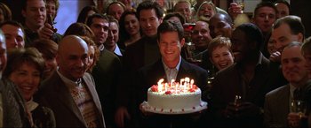 Movie still from “The Lake House” (2006), directed by Alejandro Agresti – A man holding a birthday cake surrounded by people; Medium shot, High angle