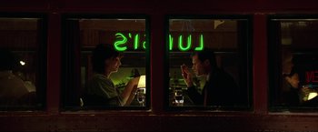 Movie still from “The Lake House” (2006), directed by Alejandro Agresti – A man and a woman sitting at a table in front of a neon sign; Medium shot, Over the shoulder angle