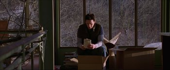 Movie still from “The Lake House” (2006), directed by Alejandro Agresti – A man sitting on a chair looking at an open box; Medium shot, Low angle