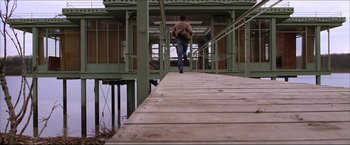 Movie still from “The Lake House” (2006), directed by Alejandro Agresti – A man is walking down a wooden bridge; Wide shot, Low angle
