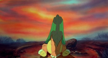 Movie still from “The Land Before Time” (1988), directed by Don Bluth – A painting of a person sitting on the ground; Wide shot, High angle