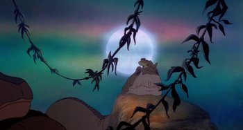 Movie still from “The Land Before Time” (1988), directed by Don Bluth – A cat sitting on top of a rock under a full moon; Wide shot, High angle