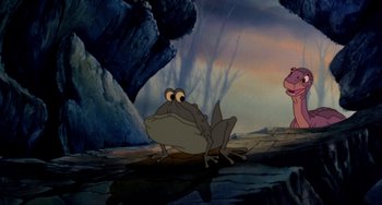 Movie still from “The Land Before Time” (1988), directed by Don Bluth – A frog is sitting on the ground next to a pink hippo; Wide shot, Over the shoulder angle
