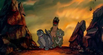 Movie still from “The Land Before Time” (1988), directed by Don Bluth – A group of three dinosaurs standing next to each other on top of a hill; Wide shot, High angle