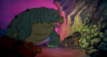 Movie still from “The Land Before Time” (1988), directed by Don Bluth – A couple of animals that are sitting in the dirt; Medium shot, High angle