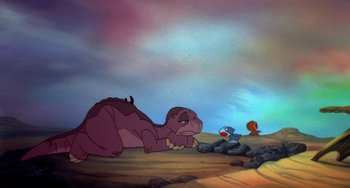 Movie still from “The Land Before Time” (1988), directed by Don Bluth – A dinosaur and a bird are sitting in the desert; Wide shot, High angle