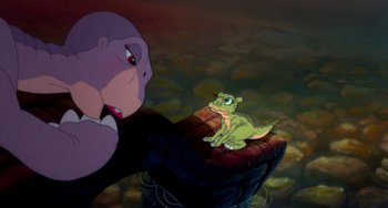 Movie still from “The Land Before Time” (1988), directed by Don Bluth – An animation of a lizard sitting next to a person; Wide shot, High angle