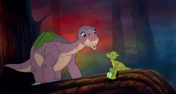 Movie still from “The Land Before Time” (1988), directed by Don Bluth – A dinosaur and a baby dragon in a scene from the land before time series; Medium shot, Over the shoulder angle