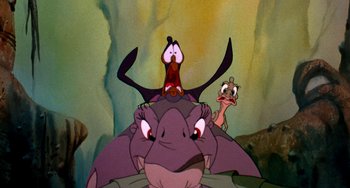 Movie still from “The Land Before Time” (1988), directed by Don Bluth – A group of cartoon characters sitting on top of each other; Close Up shot, Low angle