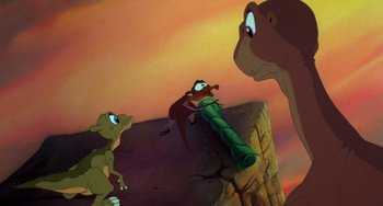 Movie still from “The Land Before Time” (1988), directed by Don Bluth – A group of cartoon characters in the background; Wide shot, Low angle
