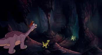 Movie still from “The Land Before Time” (1988), directed by Don Bluth – A group of dinosaurs in a dark cave; Extreme Wide shot, High angle