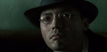 Movie still from “The Last Emperor” (1987), directed by Bernardo Bertolucci – A person wearing glasses and a hat; Close Up shot, Low angle