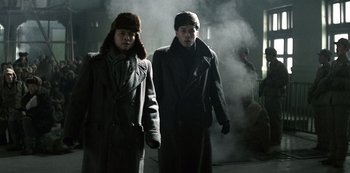 Movie still from “The Last Emperor” (1987), directed by Bernardo Bertolucci – Two men are walking through the fog in their winter coats; Medium shot, Low angle
