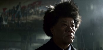 Movie still from “The Last Emperor” (1987), directed by Bernardo Bertolucci – An older man wearing a black coat and a black hat; Close Up shot, Low angle