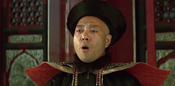 Movie still from “The Last Emperor” (1987), directed by Bernardo Bertolucci – A man wearing a black hat and a black coat; Close Up shot, Low angle