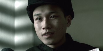 Movie still from “The Last Emperor” (1987), directed by Bernardo Bertolucci – A man wearing a black hat and a black shirt; Close Up shot, Low angle