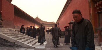 Movie still from “The Last Emperor” (1987), directed by Bernardo Bertolucci – A group of people walking down a walkway; Wide shot, Low angle