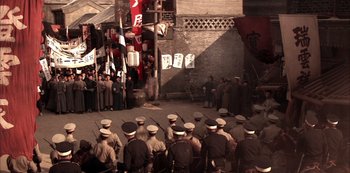 Movie still from “The Last Emperor” (1987), directed by Bernardo Bertolucci – A group of men standing next to each other in front of a building; Extreme Wide shot, High angle