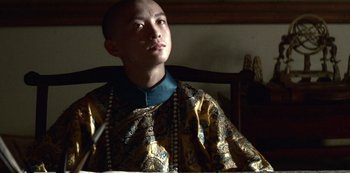 Movie still from “The Last Emperor” (1987), directed by Bernardo Bertolucci – A man sitting at a table looking up at the sky; Close Up shot, Low angle