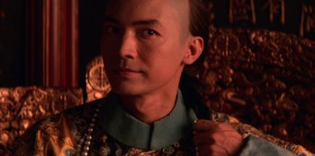 Movie still from “The Last Emperor” (1987), directed by Bernardo Bertolucci – A person wearing a necklace; Close Up shot, Low angle