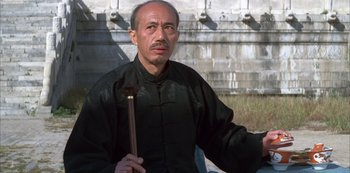 Movie still from “The Last Emperor” (1987), directed by Bernardo Bertolucci – An older man holding an axe in his hand; Medium shot, Low angle