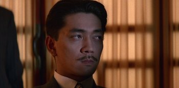 Movie still from “The Last Emperor” (1987), directed by Bernardo Bertolucci – A person wearing a suit and tie; Close Up shot, Low angle