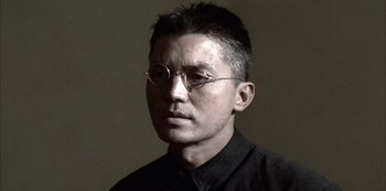 Movie still from “The Last Emperor” (1987), directed by Bernardo Bertolucci – A person wearing glasses and a black shirt; Close Up shot, Low angle