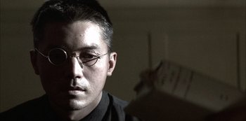 Movie still from “The Last Emperor” (1987), directed by Bernardo Bertolucci – A person wearing glasses and a black shirt; Close Up shot, Low angle
